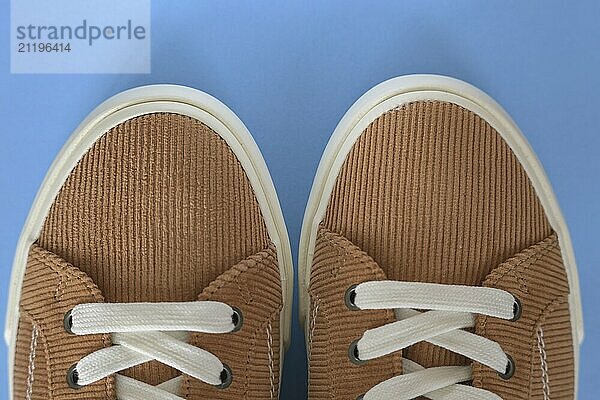 Closeup of beige corduroy sneaker shoes on a blue background