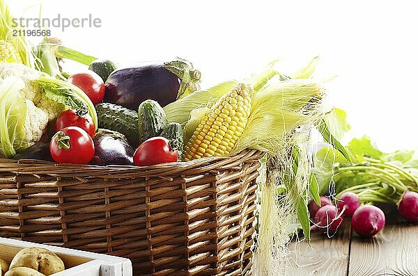 Basket of Organic vegetable food ingredients and crate of potatoes on white background