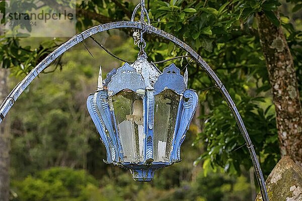 Lantern hanging on a blue metal arch against green background  Minas Gerais  Brazil  South America