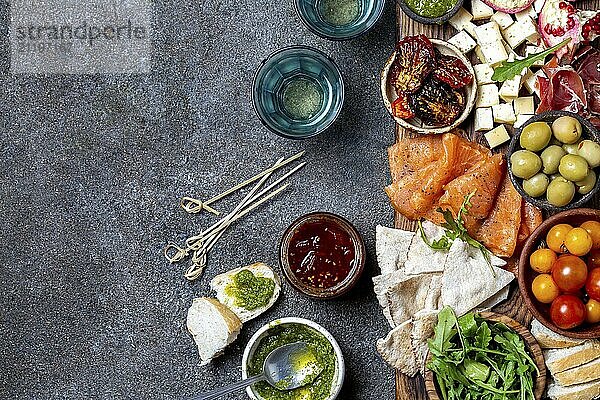 Food  Food  Antipasto. Wine set appetizer. Ham serrano  smoked salmon  dried and fresh tomatoes olive cheese  wine on board. Top view  gray cncrete background