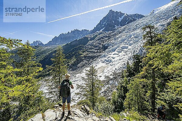 Hiker on hiking trail La Jonction  view of glacier Glacier des Bossons with sun star  behind summit of Aiguille du Midi  Chamonix  Haute-Savoie  France  Europe