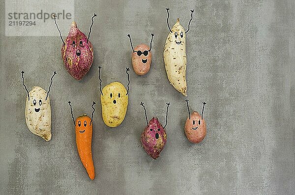 Great concept of healthy eating  vegetables with happy faces with arms up  potato  sweet potato  carrot. Gray background  polished concrete