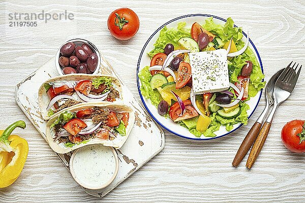 Traditionelles griechisches Essen: Griechischer Salat  Gyros mit Fleisch und Gemüse  Tzatziki Sauce  Oliven auf weißem rustikalen Holztisch Hintergrund von oben. Griechische Küche  Lebensmittel Fotografie  food photography  food photography