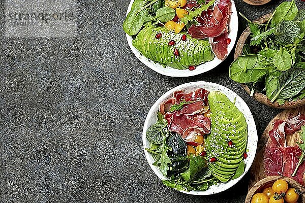 Food  Food  Low carbs bowl. Fresh salad with green spinach  rucola  avocado an ham serrano in white bowl  gray background  top view