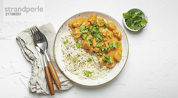 Traditionelles indisches Gericht Hühnercurry mit Basmatireis und frischem Koriander auf rustikalem weißen Teller auf weißem Betontisch Hintergrund von oben. Indisches Abendessen  Foodfotografie  food photography  food photography