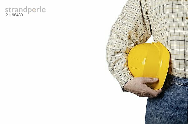 Middle aged caucasian contractor weared in blue jeans and shirt holds yellow hard hat in his hands on white background