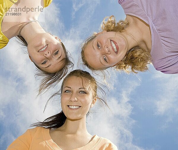 Three happy smiling teenage girlfriends under blue sky