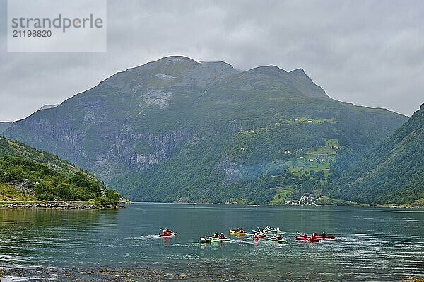 Several kayakers in a fjord surrounded by forested mountains and clouds  Geiranger  Geiranger Fjord  Stranda  Romsdal  Norway  Europe