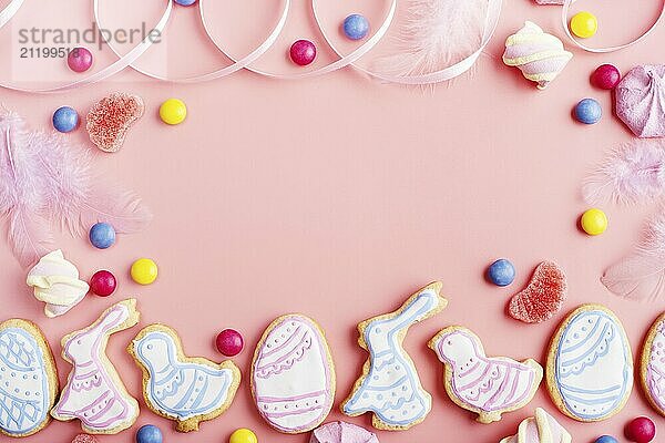 Candies and Easter frosted cookies in shape of egg chicken and rabbit on pink background. Flat lay mockup with copy space