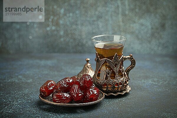 Fastenbrechen mit getrockneten Datteln während des Ramadan Kareem  Iftar Mahlzeit mit Datteln und arabischem Tee im traditionellen Glas  Blickwinkel auf rustikalem blauen Hintergrund. Muslimisches Festmahl  Foodfotografie  food photography  food photography