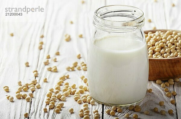 Non-dairy alternative Soy milk or yogurt in mason jar on white wooden table with soybeans in bowl aside