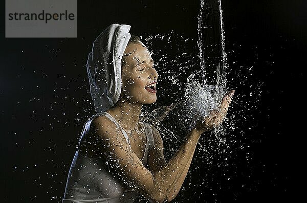 Happy girl washing her face isolated cropped shot on black background