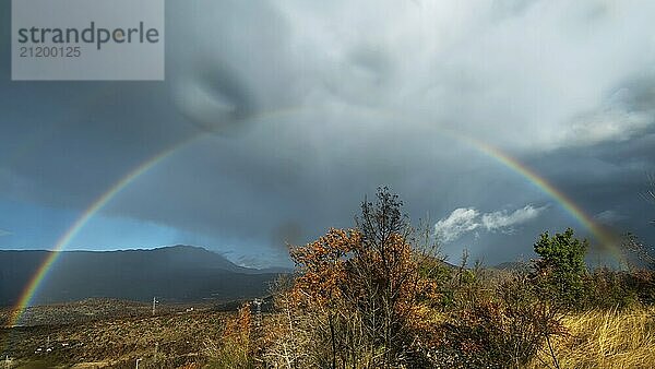 Schöne Landschaft mit Regenbogen und Wolken in den Bergen