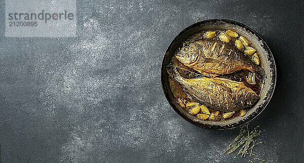 Food  Baked sea bream or dorada with onion and herbs in pan on dark background