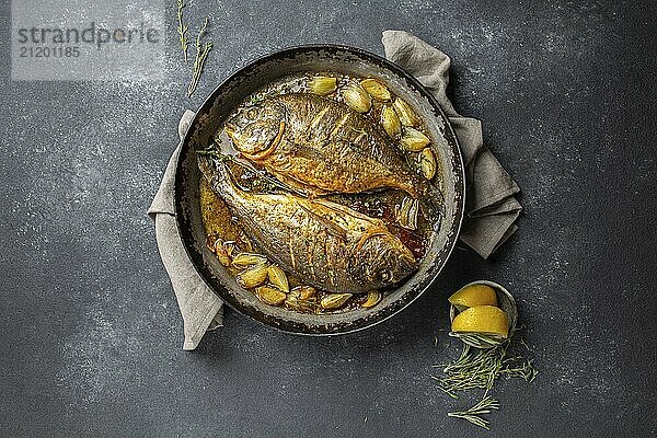 Food  Food  Baked sea bream or dorada with onion and herbs in pan on dark background