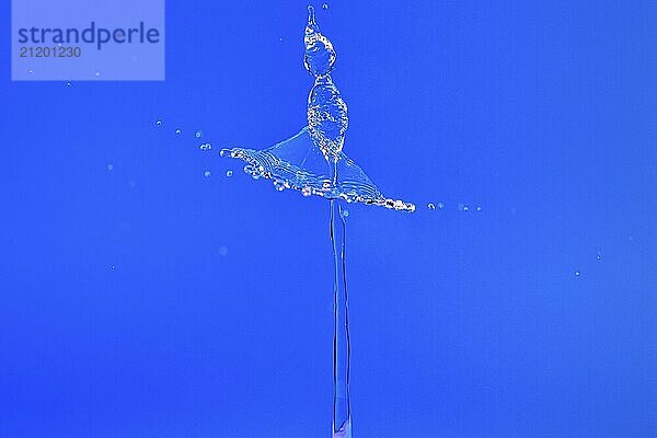 A drop of water forming a balletic figure in a clear blue background  high-speed photography