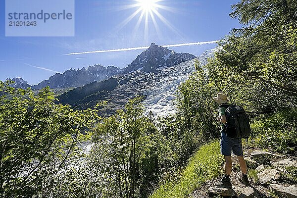 Hiker on hiking trail La Jonction  view of glacier Glacier des Bossons with sun star  behind summit of Aiguille du Midi  Chamonix  Haute-Savoie  France  Europe