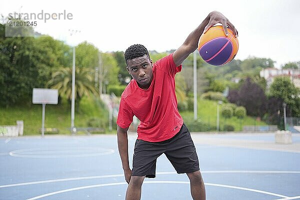 Portrait of a confident african american young basketball player dribbling in an outdoor urban court