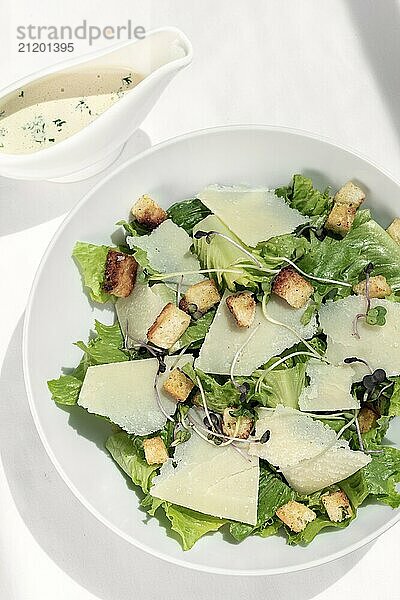 Caesar salad with parmesan cheese and croutons on white table