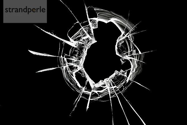 The glass hole shatters on the window from a bullet shot. Broken glass texture on a black background