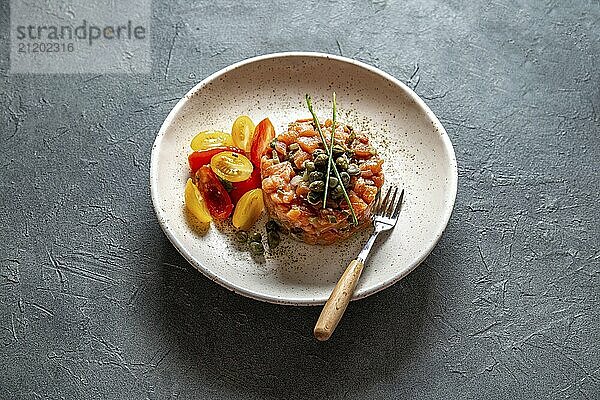 Food  Food  SALMON TARTAR with capers and purple onion on white plate  gray background