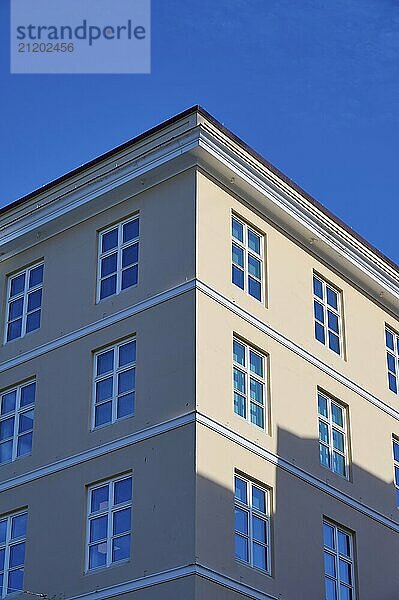 A pink corner building with many windows against a clear blue sky  Bergen  Vestland  Norway  Europe