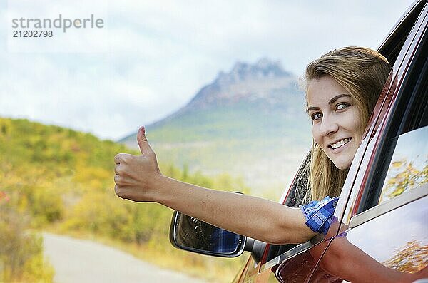 Glücklicher Fahrer Frau zeigt Daumen nach oben gegen Berge Hintergrund. Reisen Urlaub Konzept