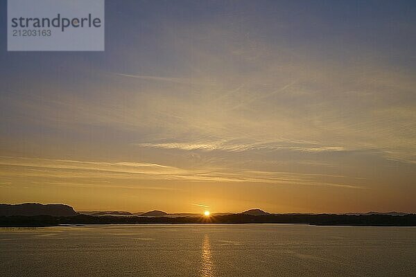 Sunrise over the sea with silhouetted mountains and an orange sky  Bergen  Vestland  Norway  Europe