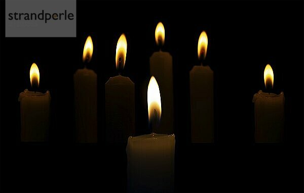 Burning candles in the dark on a black background. Religious rites  holidays or burials are accompanied by burning candles