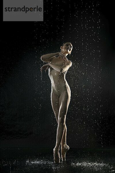 Ballerina wearing beige body dancing on pointe view under water in the dark room