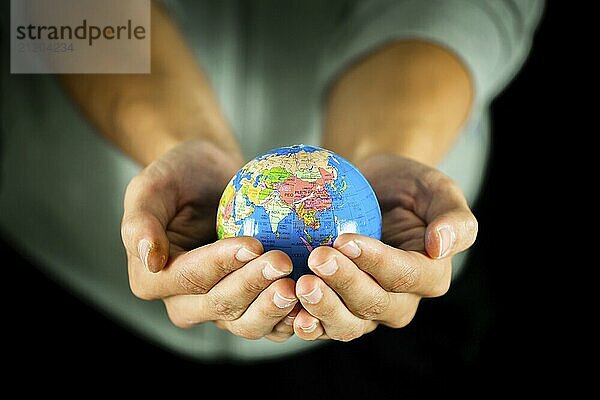 Male hands holding the Earth globe on black background