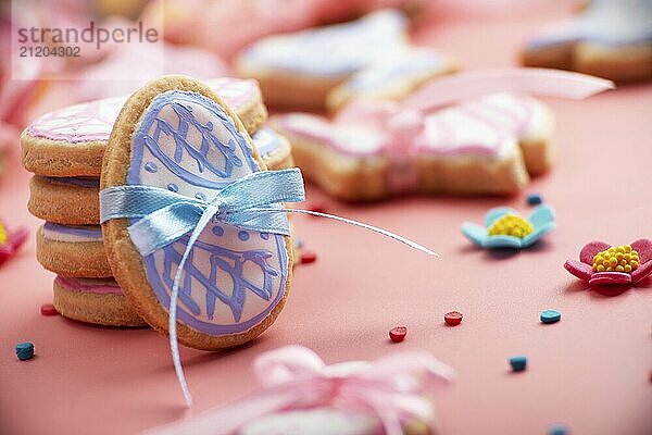 Easter baking background of frosted cookies in shape of egg on pink background