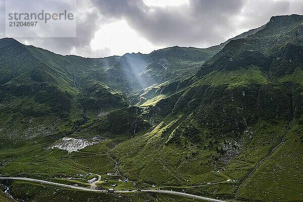 Blick auf die Transfagarasan Berge und die gewundene Straße mit Sonnenstrahlen durch die Wolken