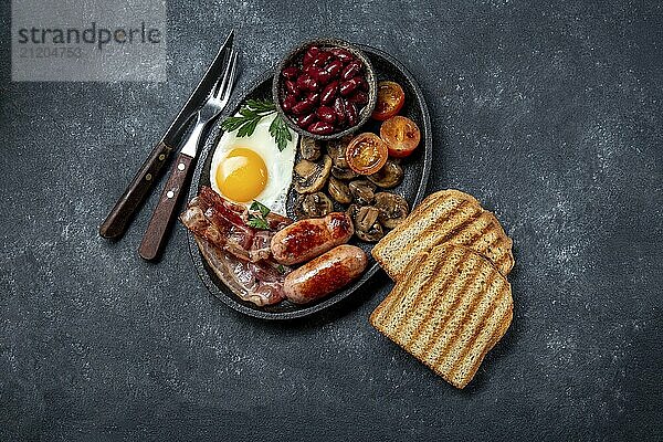 Food  Full fry up English breakfast with fried eggs  sausages  bacon  black pudding  beans  toast and coffee  dark background