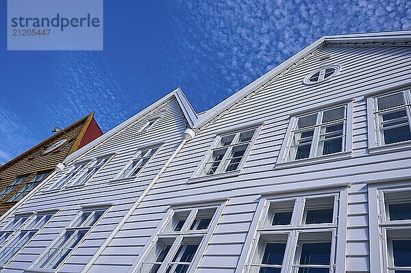 Traditional wooden houses under a blue sky with pitched roofs and multiple windows in a sunny old town  Bryggen  Bergen  Vestland  Norway  Europe