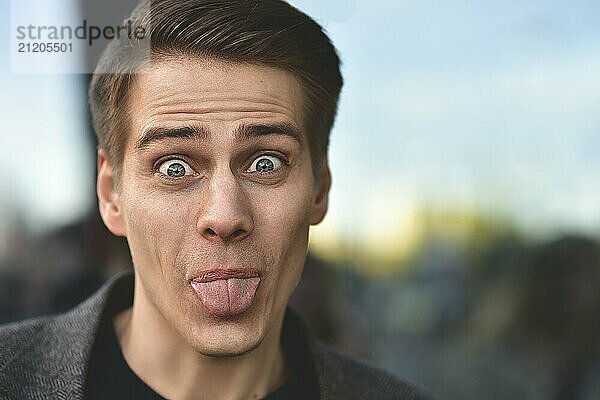 Trendy handsome happy man stay at street in gray coat and blue sweater