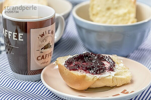 Mini butter brioche with jam and coffee mug on a light blue background