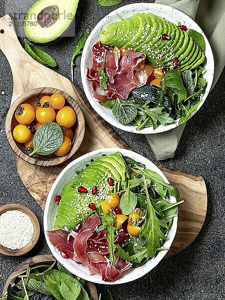 Food  Food  Low carbs bowl. Fresh salad with green spinach  rucola  avocado an ham serrano in white bowl  gray background  top view