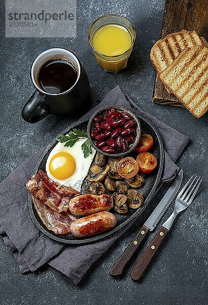 Food  Full fry up English breakfast with fried eggs  sausages  bacon  black pudding  beans  toast and coffee  dark background