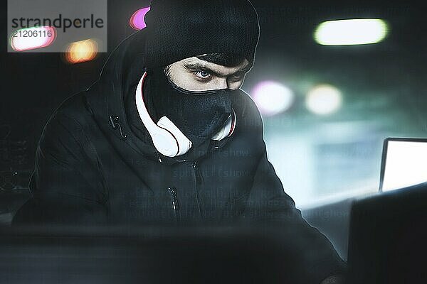 Angry computer hacker weared balaclava stealing data Via PC from His Underground Hideoutin front of black background and blue light. close portrait. hack concept