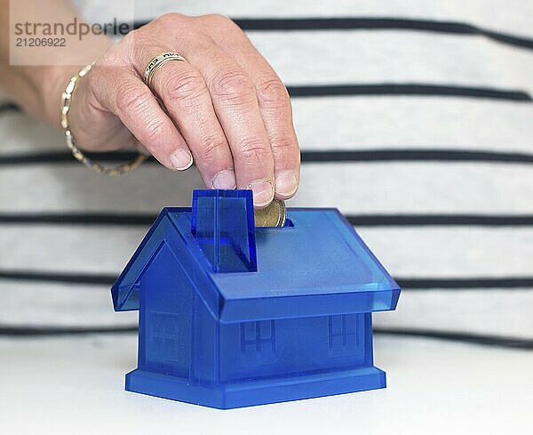 Female hand putting money in the house isolated on white background  saving money for buying a house