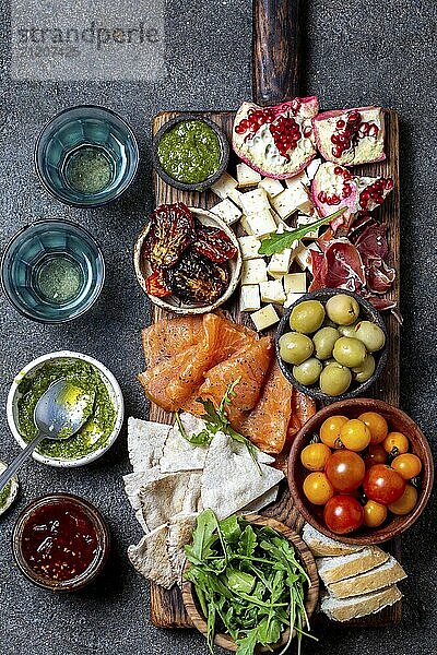 Food  Food  Antipasto. Wine set appetizer. Ham serrano  smoked salmon  dried and fresh tomatoes olive cheese  wine on board. Top view  gray cncrete background