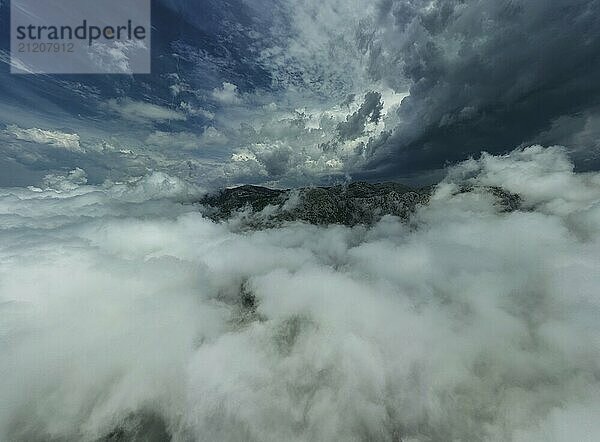 Aerial view of mountains in dramatic storm clouds. Beautiful landscape with mountain peak in fog