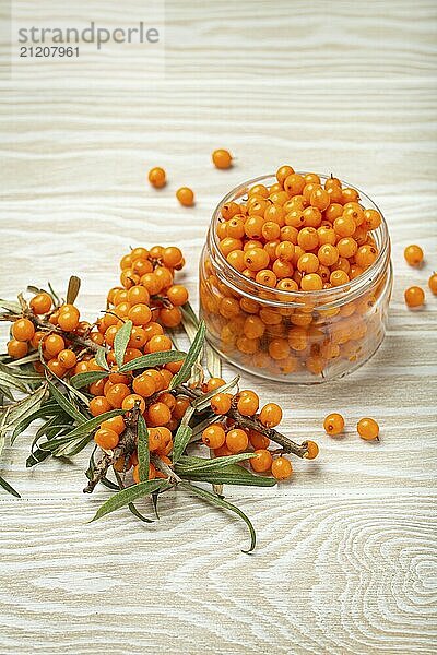 Sanddorn reife Beeren im Glas und Zweige mit Blättern von oben auf weißem hölzernen rustikalen Hintergrund  gut für Haut  Herz  Gefäße und Immunsystem  Food Fotografie  food photography  food photography