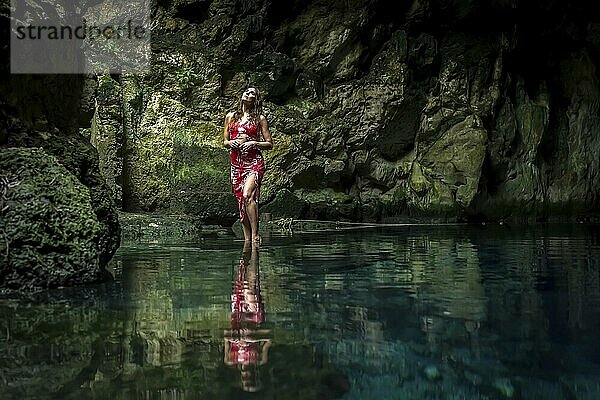 In Cuzama  Yucatan  Mexiko  schwelgt ein atemberaubendes Modell in den leuchtenden Farben des blauen und grünen Wassers einer Cenote und schafft so eine malerische Szene von natürlicher Schönheit  Mittelamerika