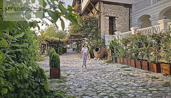 Schöne junge Frau zu Fuß auf dem Kopfsteinpflaster engen Gassen der alten Stadt Nessebar bewundern die Küste traditionellen Gebäuden umgeben von Grün. Sommerurlaub Reisen in Bulgarien