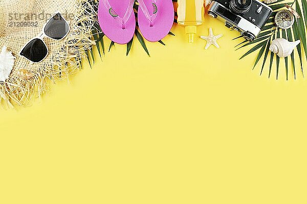 Vacation planning simple theme of chillout attributes  straw hat sunglasses flip flops film camera and palm leaves on uniform yellow background flat lay with copy-space