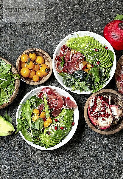 Food  Food  Lebensmittel  Schüssel mit wenig Kohlenhydraten. Frischer Salat mit grünem Spinat  Rucola  Avocado und Serrano Schinken in weißer Schüssel  grauer Hintergrund  Draufsicht