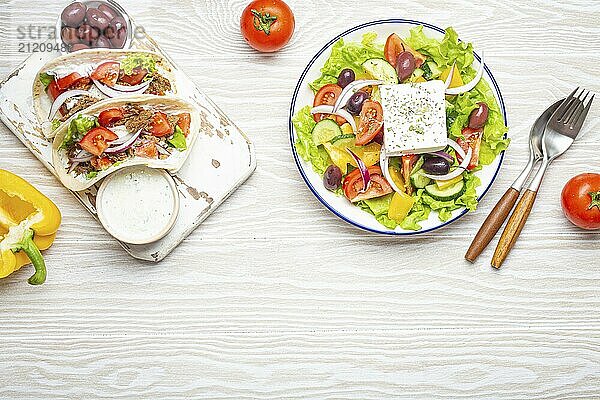 Traditionelles griechisches Essen: Griechischer Salat  Gyros mit Fleisch und Gemüse  Tzatziki Sauce  Oliven auf weißem rustikalen Holztisch Hintergrund von oben. Griechische Küche. Textfreiraum  Lebensmittel Fotografie  food photography  food photography