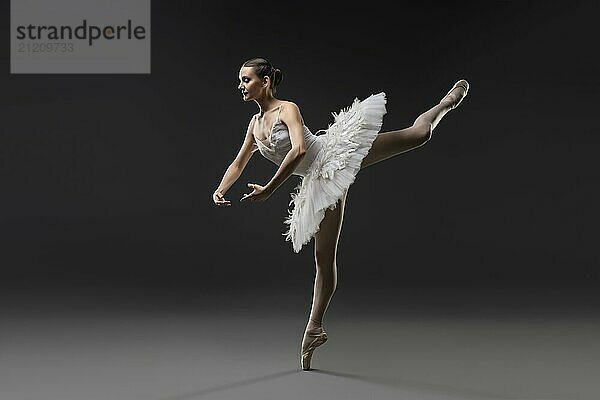 Beautiful ballerina wearing white tutu dancing on pointe view in the dark room